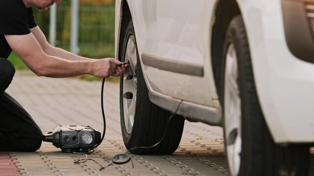 Man Inflates Tire With Portable Pump As Driver