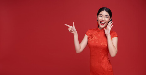 Happy Asian woman wearing red dress shouting announce and hands pointing finger to copy space...