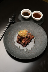Grilled and sliced beef with sauce on a black plate, close-up