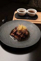 Grilled and sliced beef with sauce on a black plate, close-up