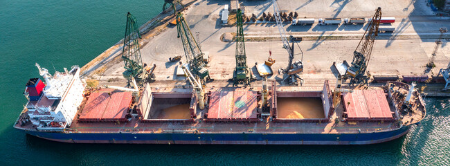 Panoramic view from a drone of a large ship loading grain for export. Water transport