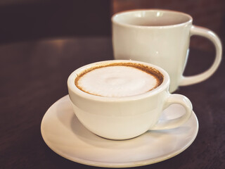 Hot cappuccino coffee in a mug Placed on the table in a warm atmosphere.