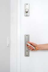 Woman hand push down metal handle, checks if the entrance door is closed - obrazy, fototapety, plakaty