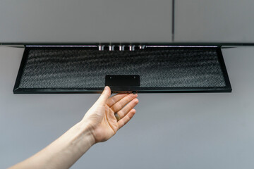 Woman hand taking aluminum mesh filter from extractor hood