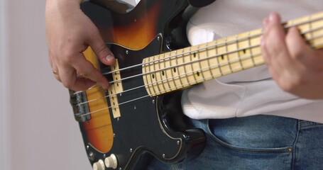 Young male professional musician skillfully playing rock, pop or other music stylish bass guitar...