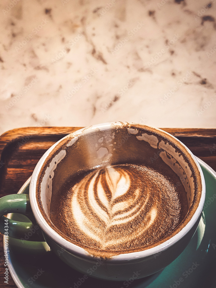 Wall mural Hot cappuccino coffee in a drinking glass Placed on the table in a warm atmosphere. There is space for text.