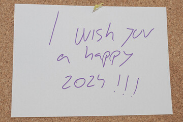 Message written with a pen on a white paper attached to a cork board with the message i wish you a...