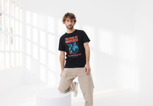 Mockup of man with wearing customizable t-shirt kneeling on plinth