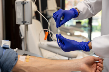 Patient man receiving infusion drip in hospital or beauty salon.