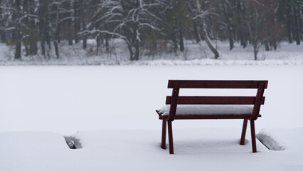 WINTER ATTACK - A bench and a fishing pier by the lake covered with snow
