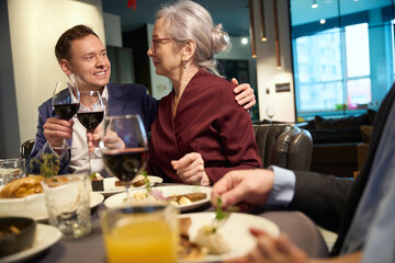Family sitting at a table clinking glasses of wine