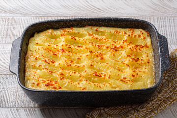 Hot casserole with creamy baked mashed potatoes. White wooden table.