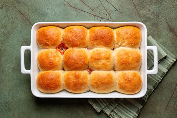 Top view of casserole with homemade sweet bread rolls, buns, made with whole wheat flour, filled...