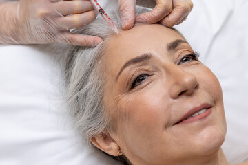 Naklejka premium Beautician making beauty injections into forehead area