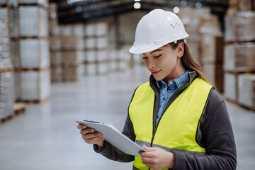 Female warehouse worker reading product order, order picking. Warehouse manager checking delivery, stock in warehouse, inspecting products for shipment. - obrazy, fototapety, plakaty