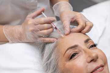 Obraz na płótnie Canvas Beautician making beauty injections into forehead area