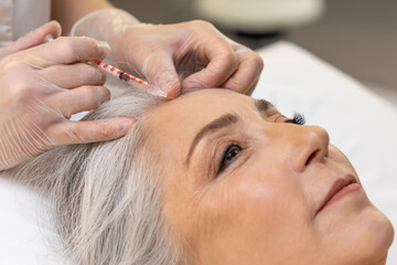 Fototapeta premium Beautiful mature woman having cosmetological procedures and looking relaxed