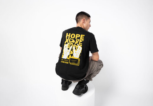 Mockup of man wearing customizable t-shirt crouching, rear view