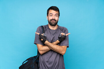 Young sport man with beard over isolated blue background pointing to the laterals having doubts