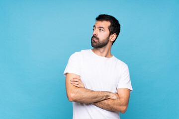 Young man with beard  over isolated blue background with confuse face expression