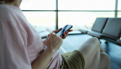 Woman typing message on mobile phone in airport building closeup. Travel mobile app concept