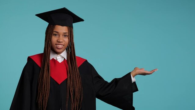 cute happy African girl in a black robe and a master's hat hand point 