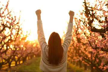 Woman raising arms celebrating sunrise in a field