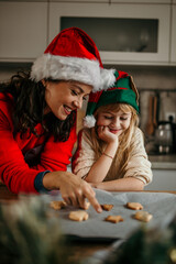 Mother and child daughter girl are cooking cookies and having fun in the kitchen. Homemade food and little helper.