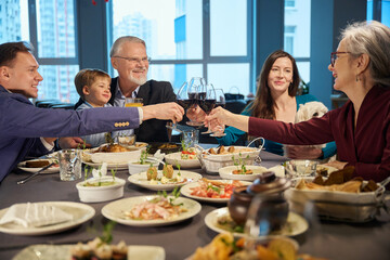 Smiling men and women raising glasses with wine celebrate Christmas together