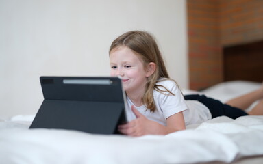 Smiling little girl looks into tablet. Baby mobile apps concept