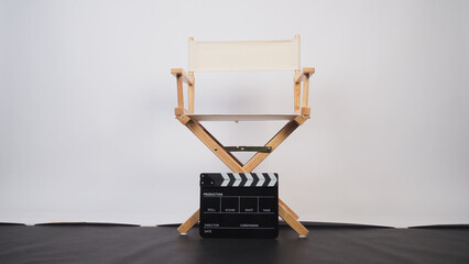 White director chair with clapper board on white background and black floor.