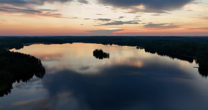Aerial view of sunset in the misty finnish forest. Flying over a lake with reflections in Finland. Drone landscape video of evening sunset. A nordic sunset over lake. Scenic colorful nature landscape.