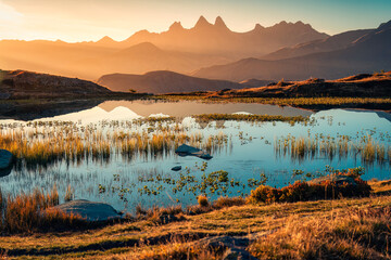 Sunrise shines over Lac Guichard with Arves massif and lake reflection in autumn at Aiguilles...