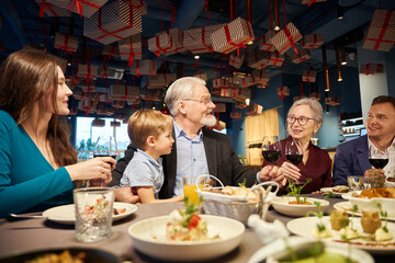 Happy family having festive dinner together celebrating New Year in restaurant