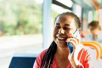 Happy African senior woman having a call with smartphone while traveling by bus