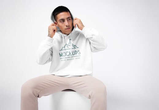 Mockup of man wearing customizable hoodie, putting hood up