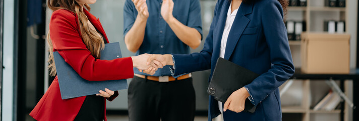 Business people shaking hands during a meeting. Two happy young businessmen and woman