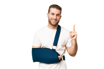 Young handsome blonde man with broken arm and wearing a sling over isolated chroma key background pointing up a great idea