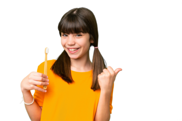 Little caucasian girl brushing teeth over isolated background pointing to the side to present a product