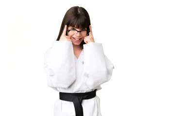 Little Caucasian girl doing karate over isolated background with glasses and surprised