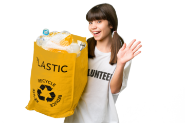 Little caucasian girl holding a bag full of plastic bottles to recycle over isolated background saluting with hand with happy expression