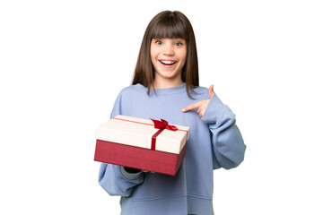 Little girl holding a gift over isolated chroma key background with surprise facial expression