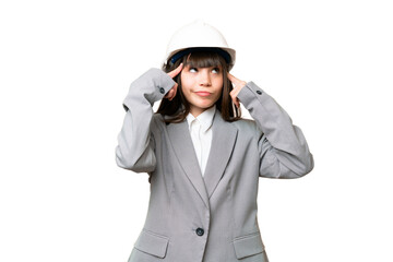 Little girl playing as a architect with helmet and holding blueprints over isolated background having doubts and thinking