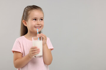 Cute girl with glass of fresh milk on light grey background, space for text