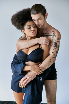 appealing young multiracial boyfriend and girlfriend in underwear hugging warmly, togetherness