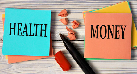 HEALTH and MONEY - words on a note sheet on a wooden light background