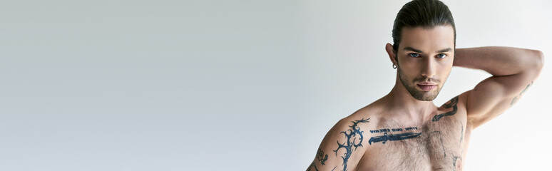 good looking man with ponytail and tattoos in comfy underwear posing on ecru background, banner