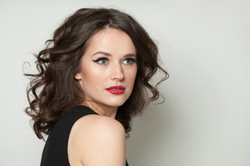 Beautiful brunette woman face close up beauty fashion portrait. Lady with makeup and dark brown wavy hair