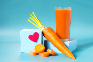 Carrot juice in a transparent glass and fresh carrots in close-up on a light background