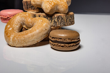 Vibrant macarons and gingerbread cookies delicately arranged on a white table against a black backdrop. Perfect for festive banners and holiday promotions.